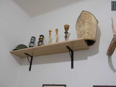 ...in cui fanno bella mostra di s� vari cappelli, una tiara da vescovo, un tamburello...